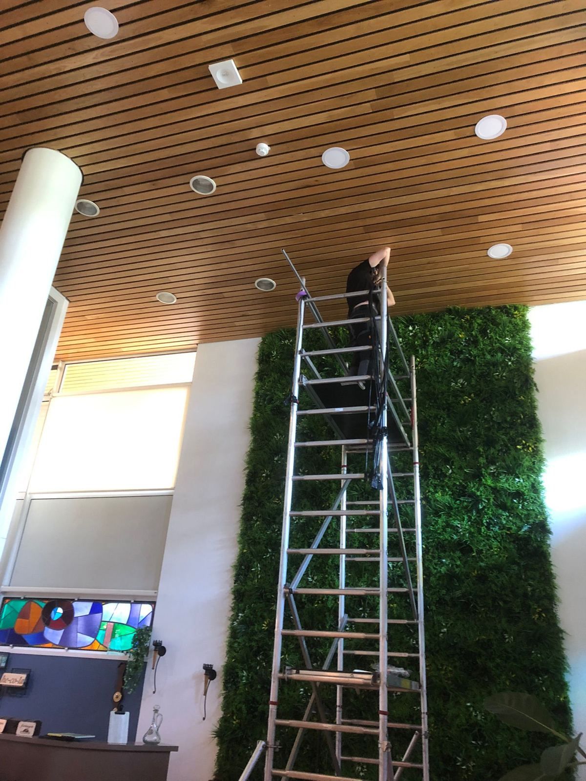 Installatie van ledverlichting in een hoge hal met groene wand